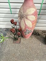 Vase and metal rose stand side by side