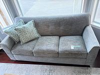 Full view of gray three-seat sofa with two accent pillows