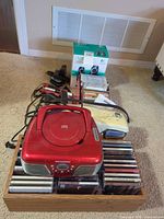 Magnasonic boombox, gold/white clock radio, CDs in wooden organizer, cables