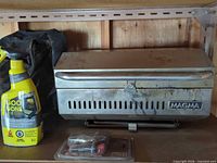 Closed Magma grill with cleaner bottle, parts kit and fabric bag visible