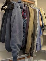Multiple jackets, sport coats, shirts on closet rod