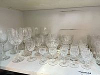 Full set of assorted cut and etched crystal glasses on shelf