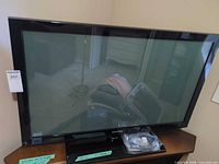 Front view of Samsung TV on stand with cables packaged in front