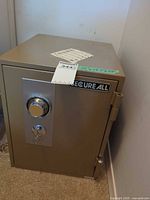 Front view of beige SecureAll safe showing combination dial, key lock and logo