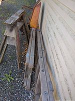 Ladders leaning against wall beside sawhorse and wheelbarrow
