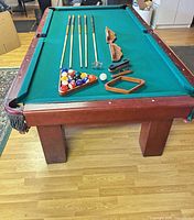 Full view of pool table with cues and accessories laid out