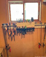 Full view of clamp collection on plywood rack under window