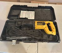 Saw inside open hard case with blades, cord and manual visible