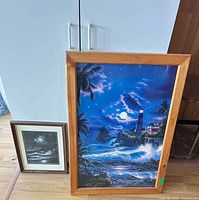 Both framed prints leaning against cabinet for size comparison