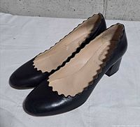 Side view of right shoe showing scalloped edge and block heel