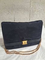 Front view showing monogram canvas, gold clasp, chain strap