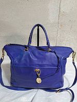 Front view showing handles, shoulder strap, gold clasp and medallion