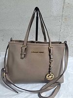 Front view showing handles, strap, logo, charm