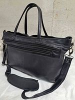 Front view showing exterior zip pocket, dual handles, shoulder strap attached