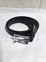 Coiled black leather belt showing buckle and texture