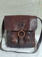 Front view showing flap, brass ring, buckle, strap and leather condition