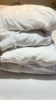 Stack of four folded white king-size cotton bed linens