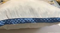 Side view of white pillow showing blue quilted gusset