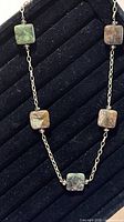 Full view of necklace showing chain and five square stone beads