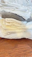 stack of folded white, cream and gray cloth rags on wooden surface