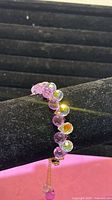 Side view of bracelet showing faceted purple iridescent beads on display stand