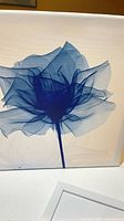 Front view of blue translucent flower artwork in white frame