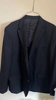 Front view of black dress jacket on hanger