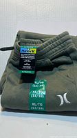 Folded olive green Hurley jogger showing brand hangtag and size sticker