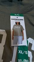 Front of folded olive green Scotch & Soda T-shirt showing white PARIS print and tag