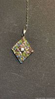 Front view of square pendant with multicolour rhinestones and central clear stone on chain