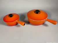 Both Le Creuset orange sauce pans with lids, side-by-side for size comparison