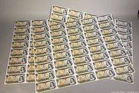 Front sides of overlapping uncut $1 sheets displaying 40-note layout