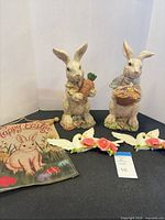 Group view of both rabbit figurines, two dove plaques and garden flag