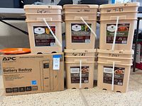 Group shot of six Wise Company buckets and boxed APC Back-UPS