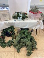 Multiple holiday decorations including wreath, garland, centerpiece, lights box, metal tree frame