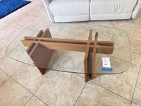 Full view of oval glass coffee table showing glass top and oak base