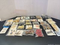 Overview of all small zip bags containing assorted costume jewellery pieces laid out on table