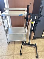 White metal 3-shelf cart beside black TV stand