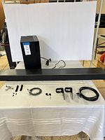 Soundbar, subwoofer, cables, brackets and hardware displayed