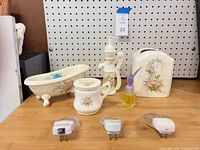 Group shot showing all ceramic pieces, perfume bottle and three night lights on shelf