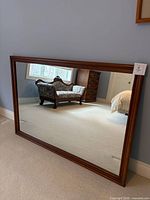 Front view of rectangular cherry framed mirror reflecting room