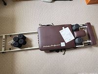 Top view of the Pilates Performer reformer showing padded carriage, foam rollers, and manual