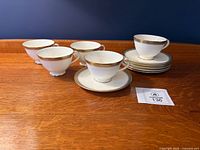 Five teacups and five saucers displayed on wooden surface