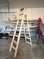 Full view of tall wooden folding ladder standing open in garage