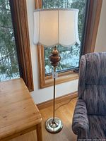 Full view of floor lamp beside table and chair showing overall height and base