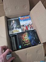 Open box showing visible DVD titles Ultraviolet, Dennis the Menace collection, Life and several jewel cases