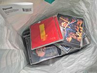 Open tote bag showing stacked CD jewel cases, top disc Beatles 1, others partially visible