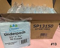 Open box showing multiple sealed packs of Secure SP13150 underpads and external carton with size and count details