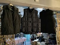 Three vests hanging side by side showing overall style and colors