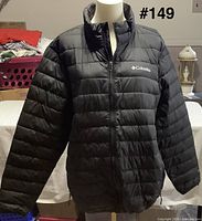 Front view of black Columbia quilted jacket on mannequin showing full zipper and logo